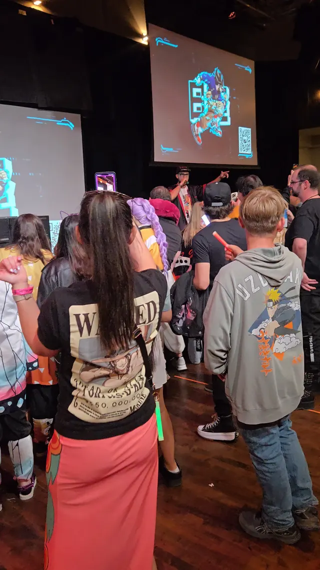 crowd gathered on floor near screens with a host on mic