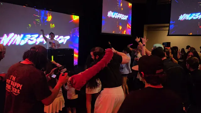 DJ NINJ3FF3C7 performing behind booth as crowd dances